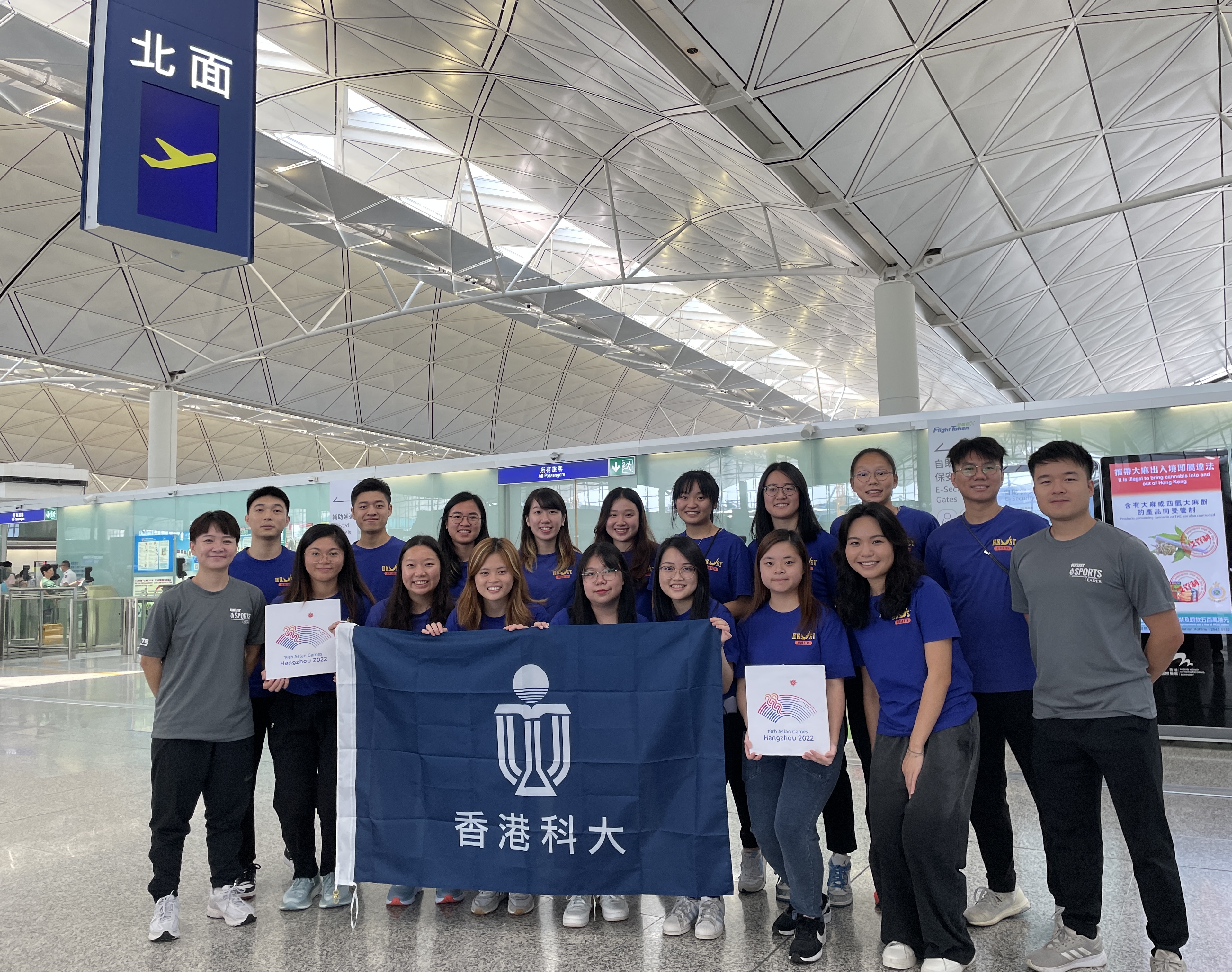 16名科大學生義工在機場手持杭州亞運標誌合影，他們於今日（9月21日）正式啟程前往杭州。