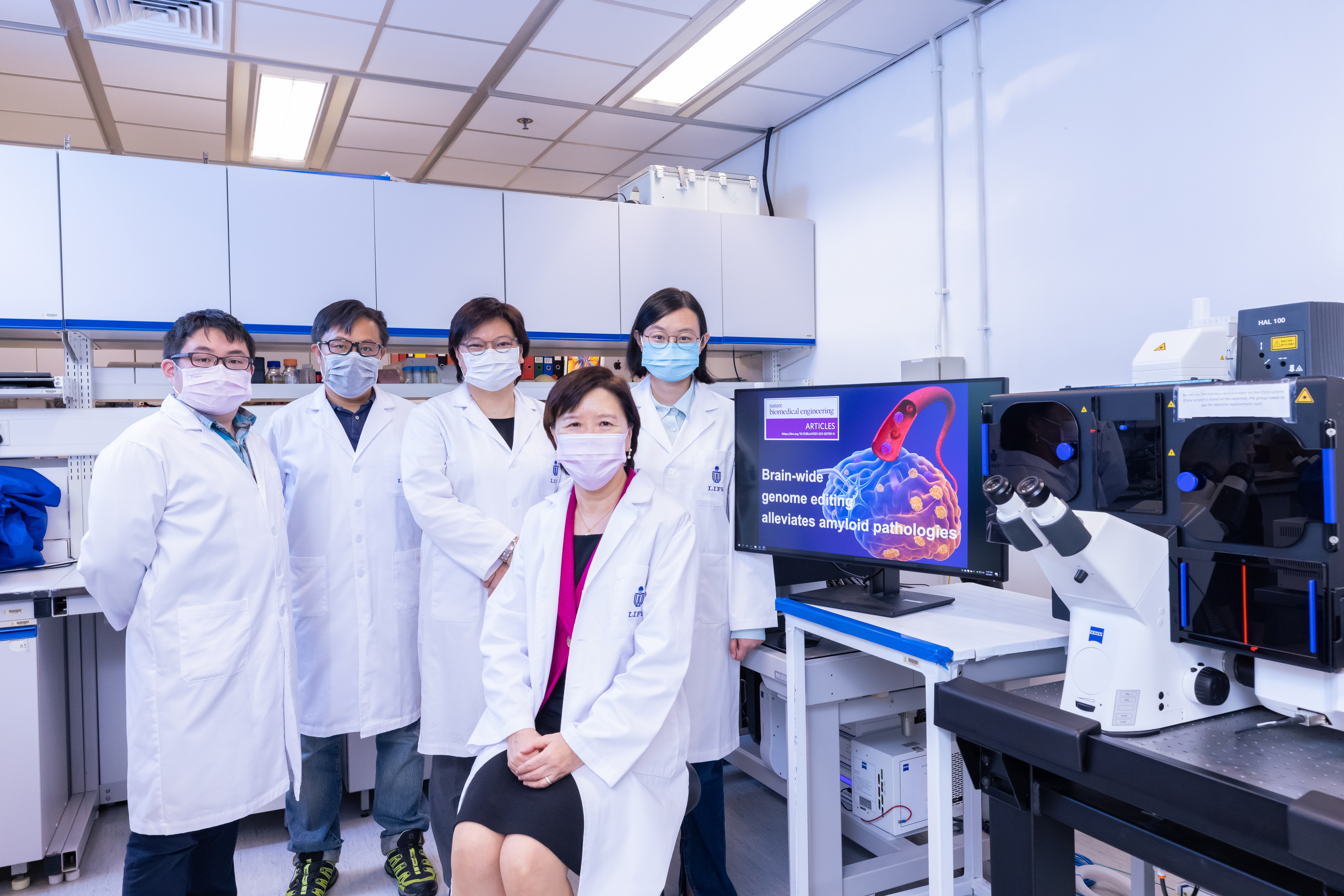 HKUST's Vice-President for Research and Development, Prof. Nancy Ip (second right) and her research team members - including doctoral student and co-first author of this research paper, Ms. Stephanie DUAN Yangyang (first right) - used the confocal imaging system (pictured) to demonstrate how disruption of a familial Alzheimer's disease mutation by genome editing strategy reduces disease pathology. 