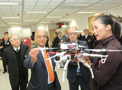  郑家纯博士(左二)由科大校董会主席廖长城先生(左一)及校长陈繁昌教授(左三)陪同，参观大楼内的机器人研究所。